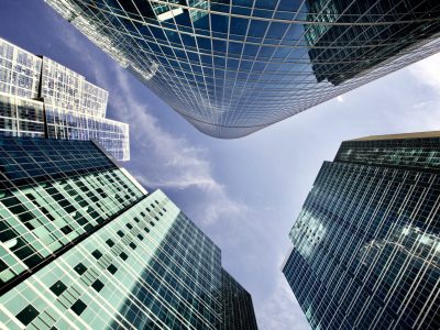 Office and residential skyscrapers against bright clear blue sky. Commercial real estate. Glass and metal in urban architecture. Modern facade design. Modern business city district. Office buildings exterior. Financial city district. Reflections and highlights in glass. Wide angle city photography.